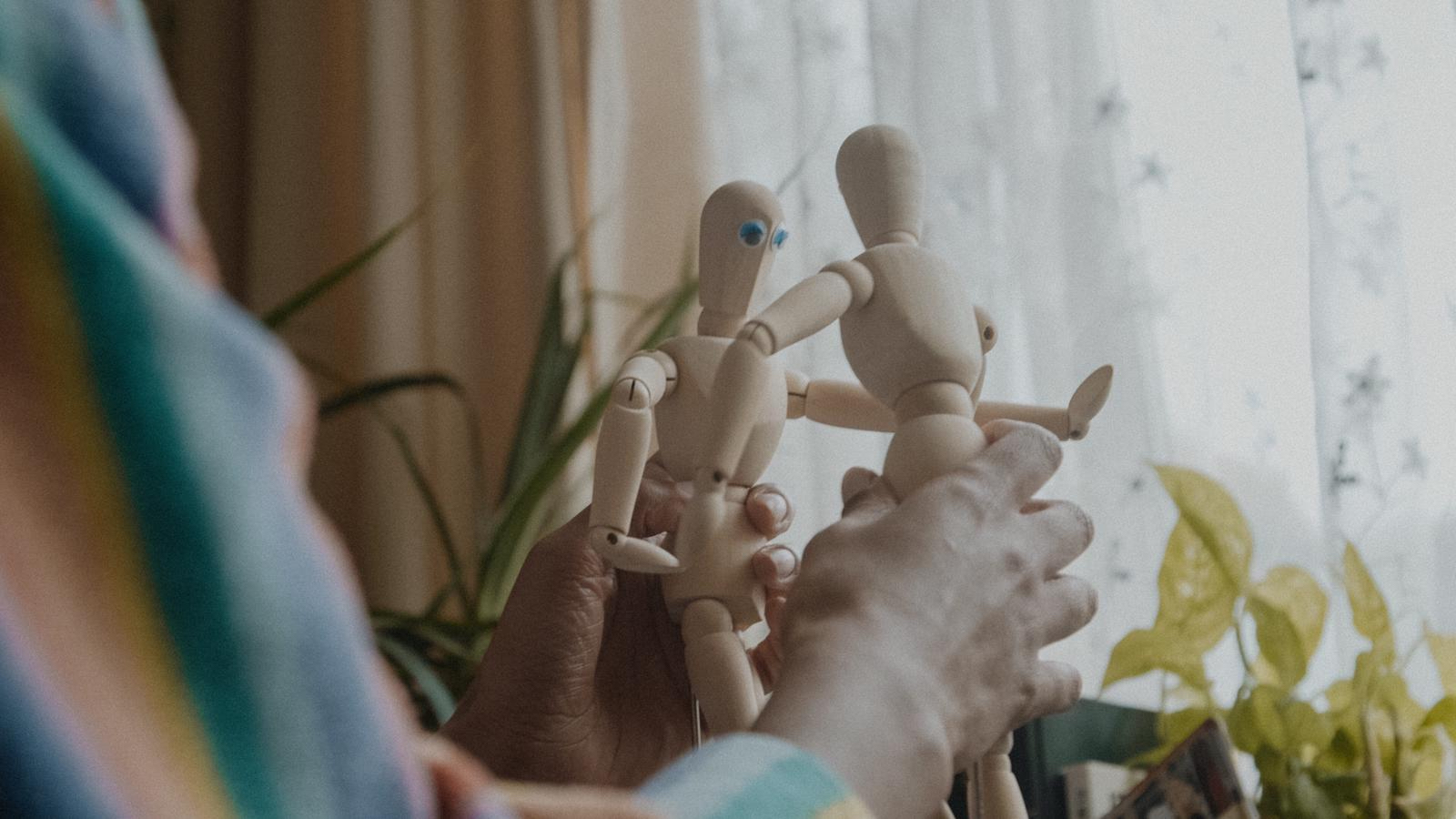 A hand holding two small mannequins
