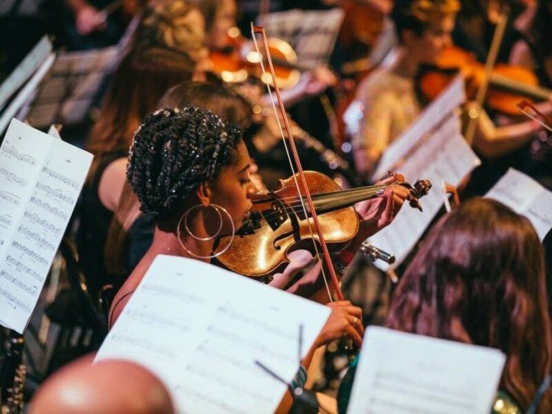 close up focusing on Almaz Ohene within an orchestra playing the violin